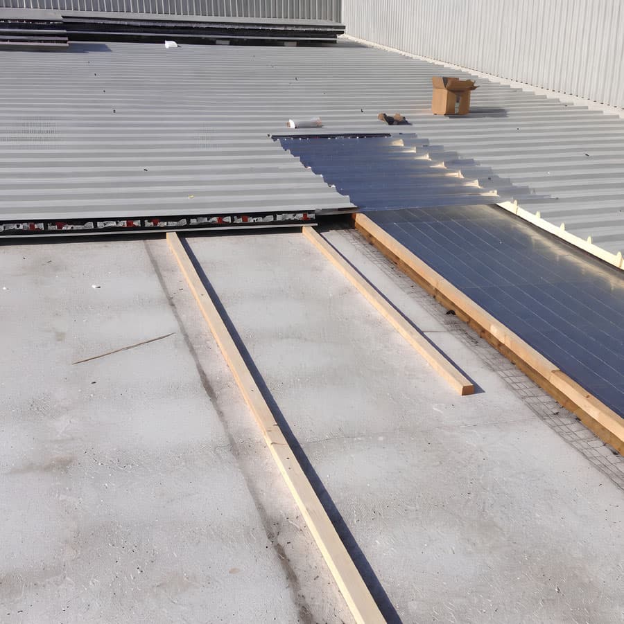 Fase di installazione di pannelli sandwich coibentati su un tetto industriale con dettaglio dello strato isolante e della struttura di supporto.